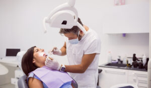 dentist-examining-female-patient-teeth Ainos Dental
